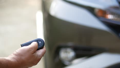 hand holding car remote control near a car