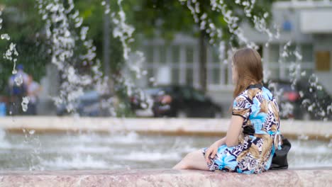 woman sitting by a fountain in the city