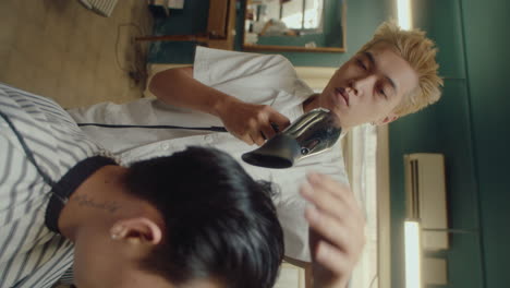 asian barber drying hair of client after giving a haircut