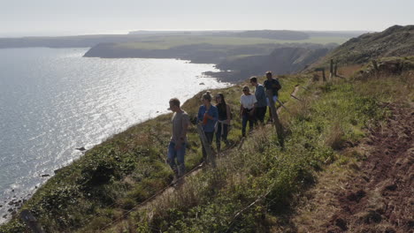 drone shot of group of friends hiking along cliffs on coastal path