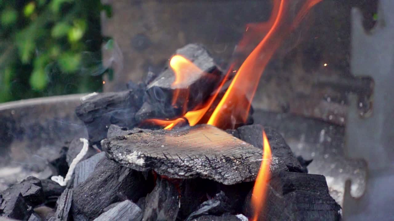 느린 움직임의 클로즈업  ⁇ 은  ⁇ 은 날 동안 그릴에 나무와 함께 불타는 석탄에 초점을 맞추고 있습니다.