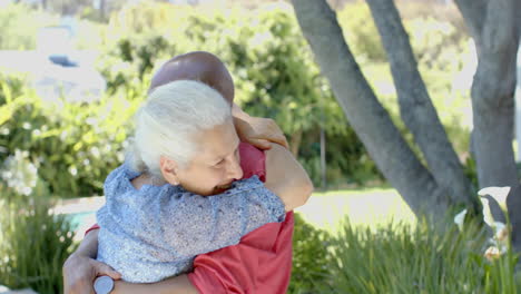 una feliz pareja biracial se abraza en el jardín soleado de su casa, en cámara lenta.