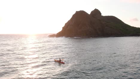 man kayaking along na mokulua isles in hawaii at sunrise, aerial view