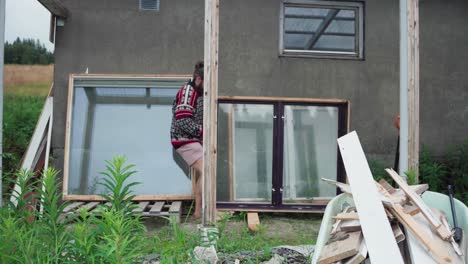 hombre tirando de ventanas de vidrio para construir un invernadero - toma amplia