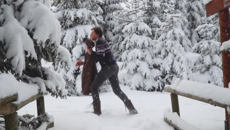 hombre caucásico con ropa informal de invierno caminando en el bosque de invierno y agarrando su chaqueta marrón para usar