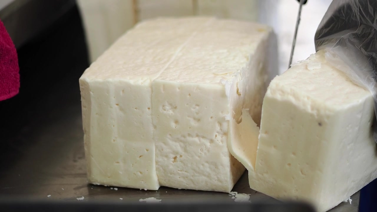 Chef Cutting a Large Block of Fresh White Cheese