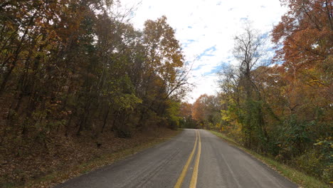 pov from car driving in the road along the forest at devil's den state park during autumn in washington, arkansas, united states