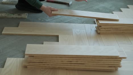 worker installing wooden flooring with hammer and tapping block