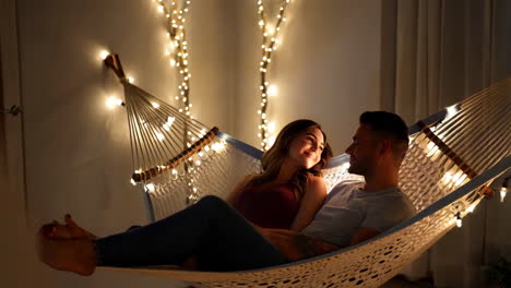couple relaxes in a hammock surrounded by string lights