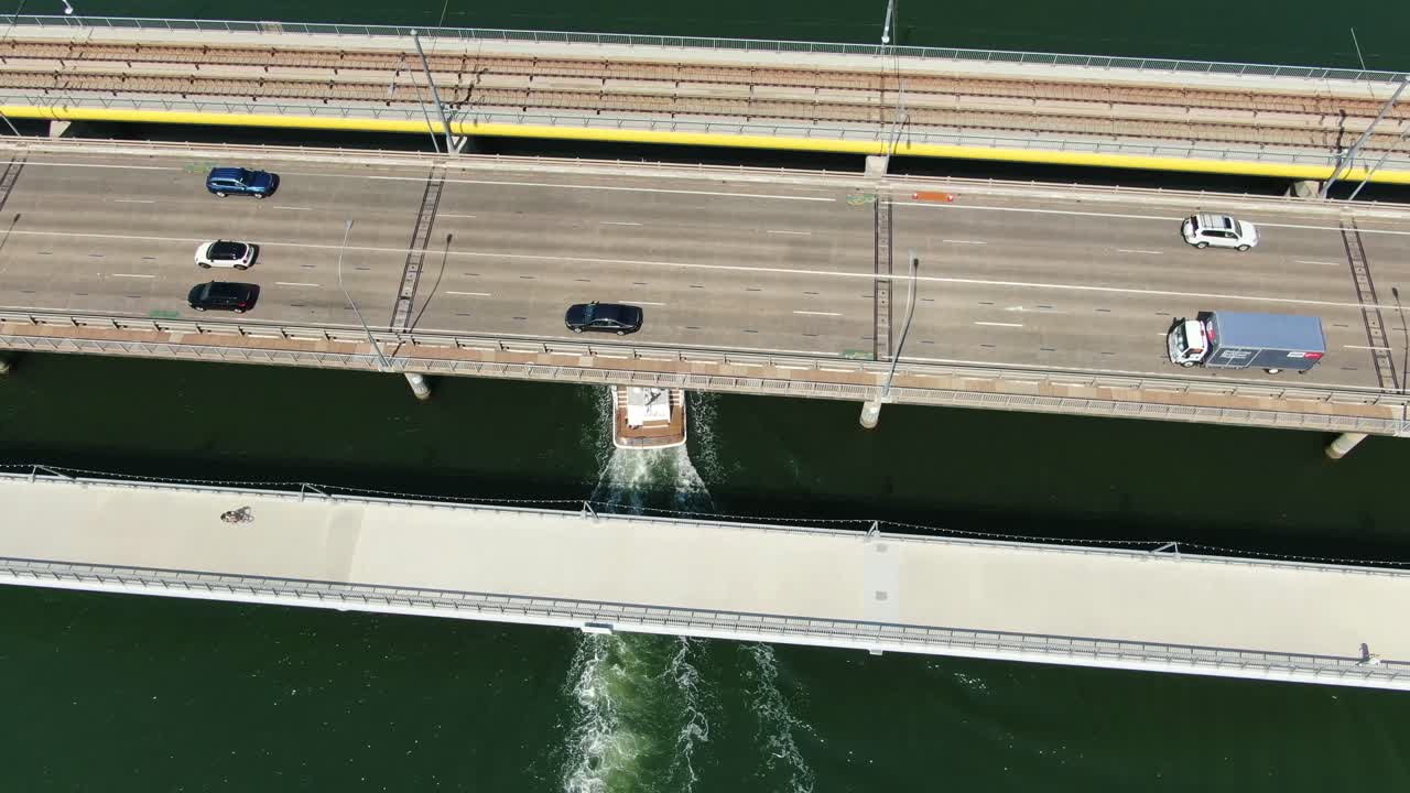 호화로운 선박은 밝은 여름날 교통 체증으로 혼잡한 다리 아래를 통과합니다.