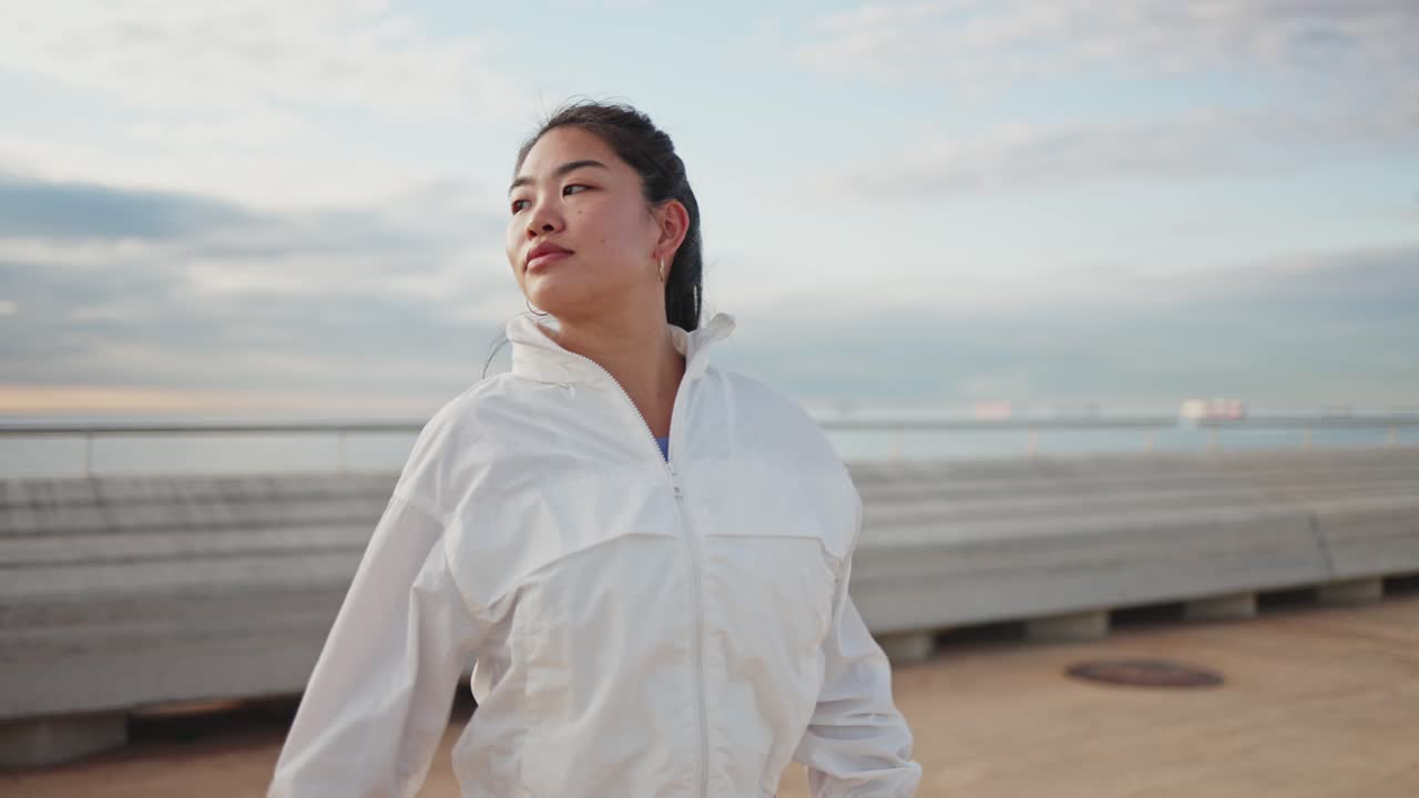 水辺の屋外でストレッチする若いアジア人女性。