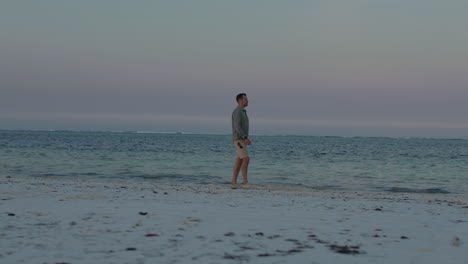 man walking on a peaceful beach at sunset