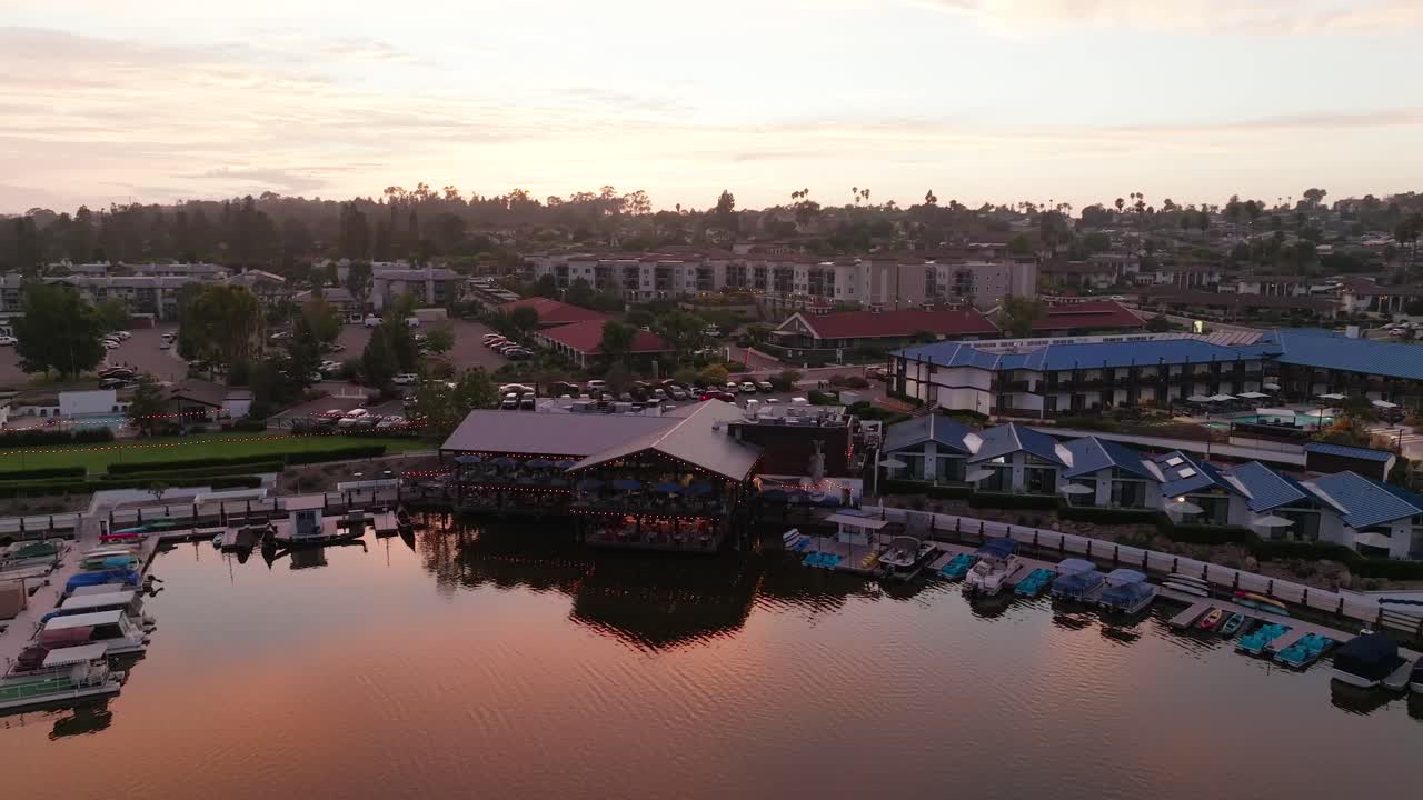 Riprese drone 60FPS con avvicinamento e inclinazione che mostrano l'Almafi Bar sul Lago San Marcos a San Diego, California, USA, al crepuscolo.