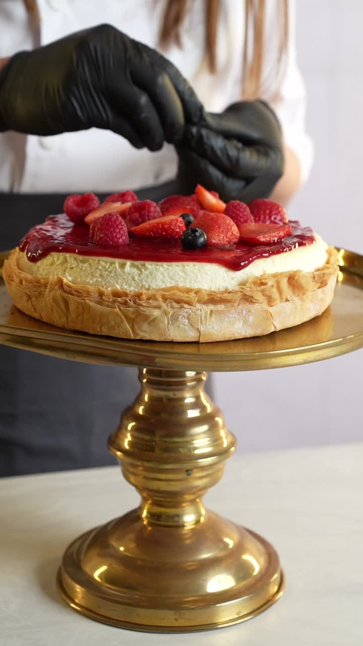 Close-up of a delicious cheesecake with fresh berries being decorated by a chef