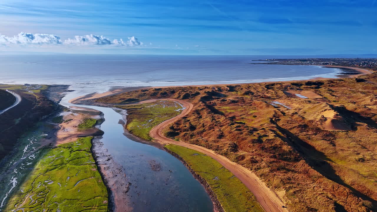 Paesaggio costiero con estuario fluviale e orizzonte oceanico lontano. Ripresa aerea che mostra una foce di fiume che si congiunge a una spiaggia sabbiosa con onde che si infrangono in lontananza