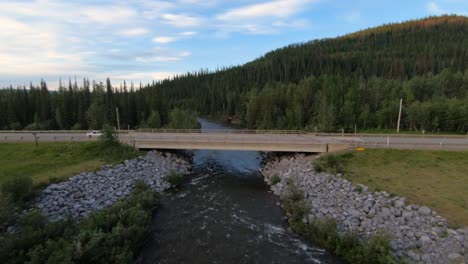 a white sports car seen driving over a bridge that goes over a river