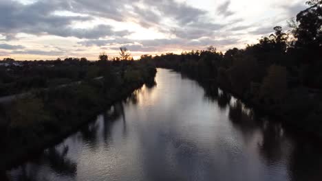 drone flying over river during sunset near a forrest