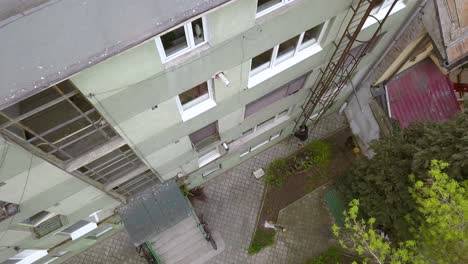 Overhead-Aerial-Drone-Wide-Shot-of-a-Young-Adult-Male-Parkour-Free-Runner-Climbing-Down-a-Fire-Escape-on-the-Side-of-a-Building