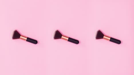 tres pinceles de maquillaje girando sobre un fondo rosado brillante. detenga el movimiento