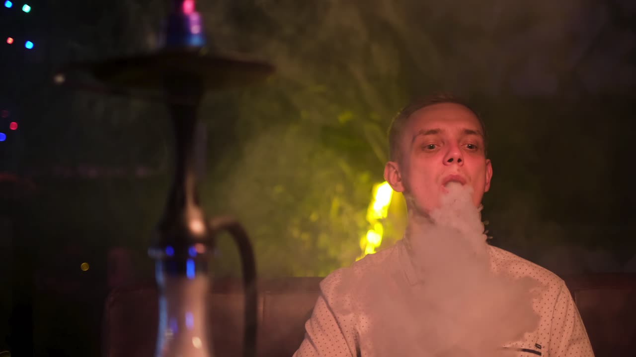 hombre fumando narguile en un club nocturno
