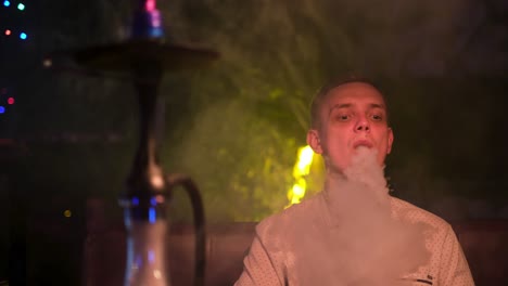 man smoking hookah at a nightclub