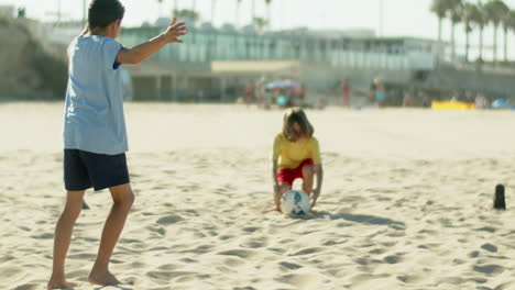 Slow-motion-of-boy-kicking-soccer-ball-to-goalkeeper-on-seashore