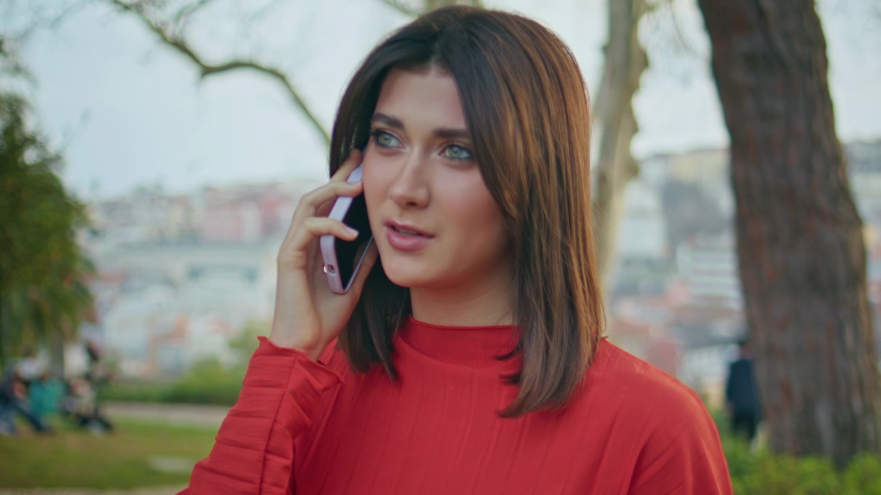 Chica morena hablando por teléfono móvil en un parque de la ciudad. Primer plano de mujer hablando al aire libre