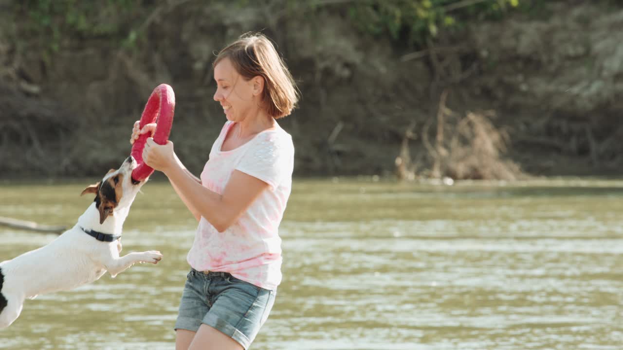 강 근처에서 개와 놀고 있는 여자