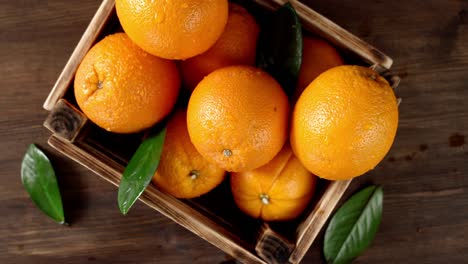 las naranjas jugosas con hojas en una caja de madera giran lentamente.
