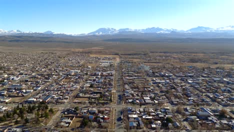 low descending aerial of malargüe in southern mendoza with clear view of the andes mountain range and structured urban grid amid arid landscape and sharp geographic contrast in the background