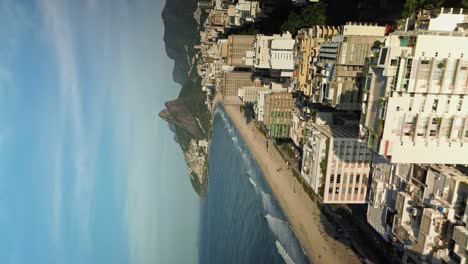 drone flying above multistory buildings along sandy beach in rio de janeiro - vertical video