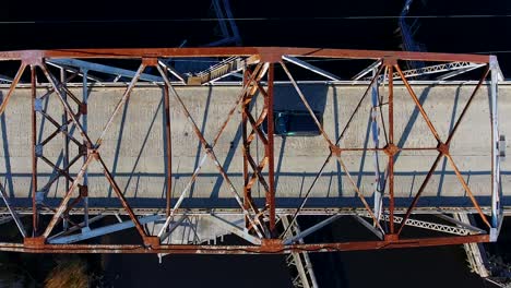 Birds-eye-view-of-an-old-bridge,-a-black-car-passes-through