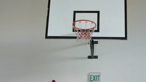 playing basketball, woman shooting ball towards hoop in indoor court