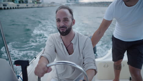 man smiling and driving a boat on the water