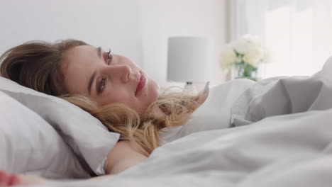 beautiful caucasian woman waking up in bed after restful sleep smiling happy ready for new day