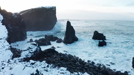 moviéndose hacia el mar desde el suelo con el dron mientras la gente toma fotos de las altas olas en la nevada islandia