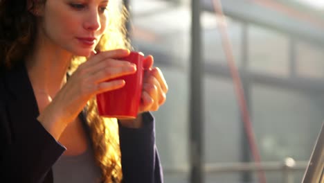 female executive using digital tablet and mobile phone while having coffee