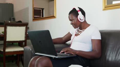 african lady sitting on couch working on laptop