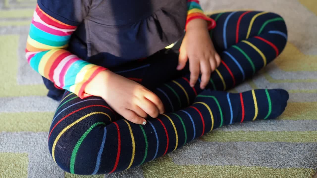niña pequeña con leggings a rayas y una camiseta arco iris
