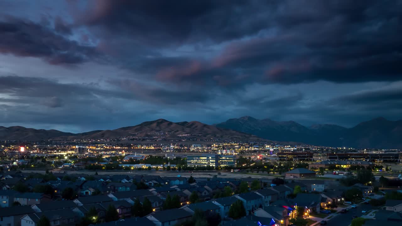 Lehi, Utah and Silicon Slopes from twilight to nighttime with the FrontRunner commuter train passing through - sliding aerial hyper lapse