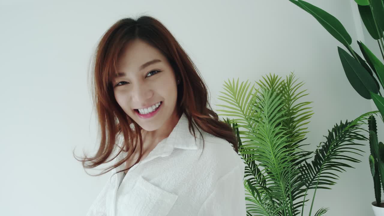 아름다움 여자는 행복한 감정으로 춤을 추고 흰색 방에서 웃고 있습니다.