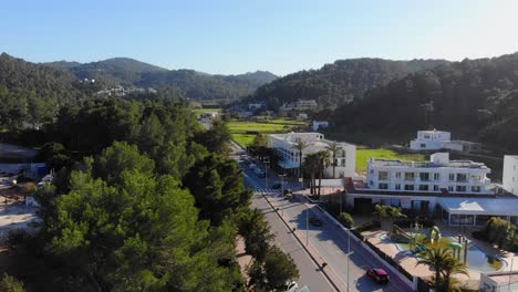 drone descendiendo por una carretera con algunas casas con una piscina verde en ibiza