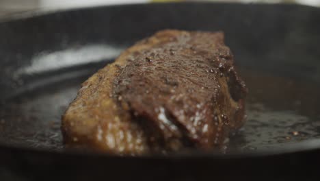 chef turns frying steak from one side to another