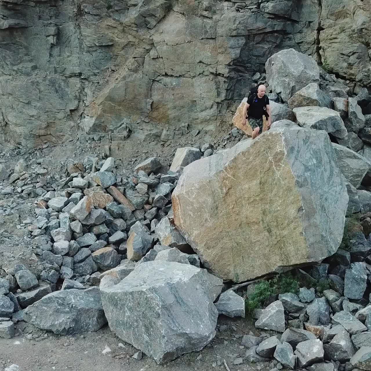 Man Walking along Giant Rocky Mountain Wall. Travel concept. Aerial view