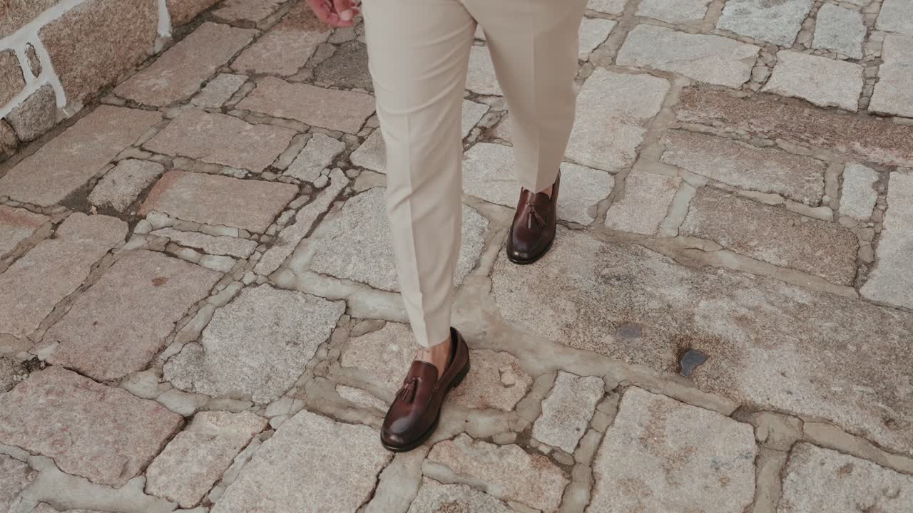 primer plano de unos zapatos de cuero marrón caminando sobre adoquines