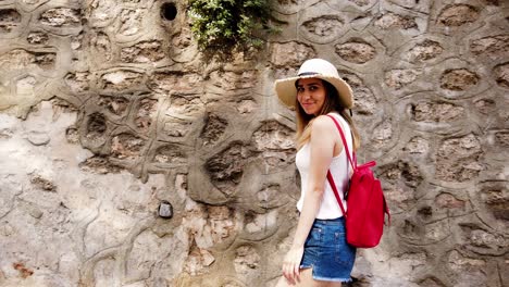 slow motion:beautiful young girl touches wall while walking on the street