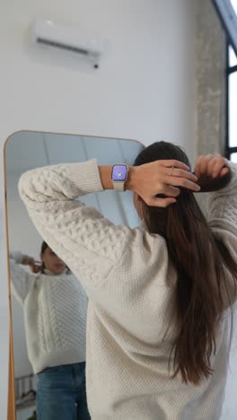 woman looking at herself in a mirror while styling her hair