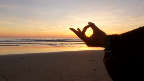 hand silhouette of a woman who is doing yoga in front of the sea