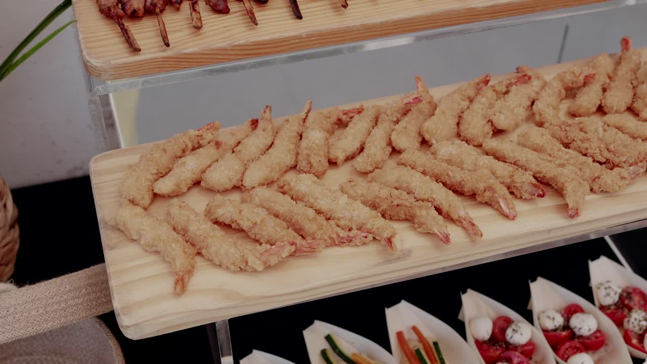 deep fried tempura shrimp arranged on a wooden tray at a catering buffet event