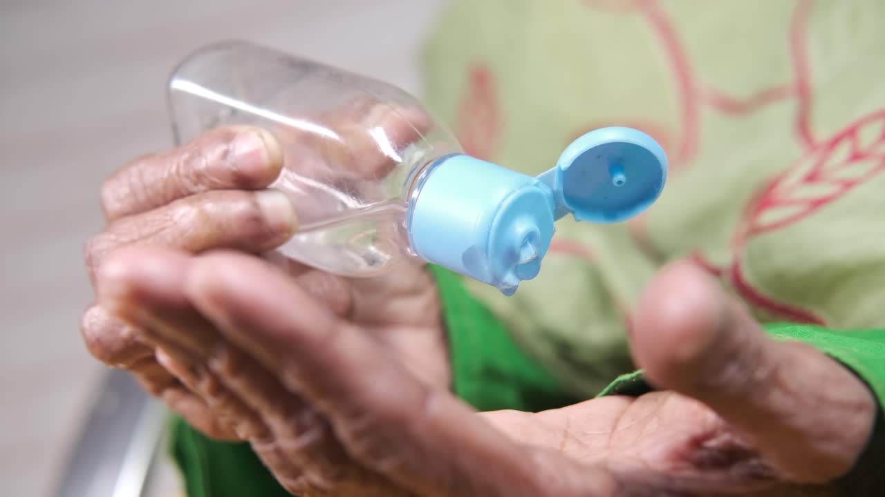 persona de edad avanzada que aplica desinfectante para las manos